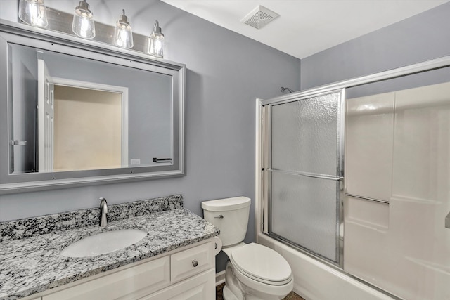 full bathroom with enclosed tub / shower combo, vanity, and toilet