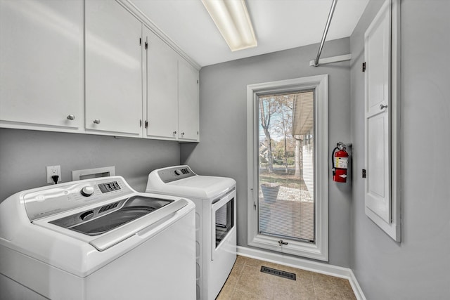 washroom featuring washing machine and dryer, cabinets, and light tile patterned floors