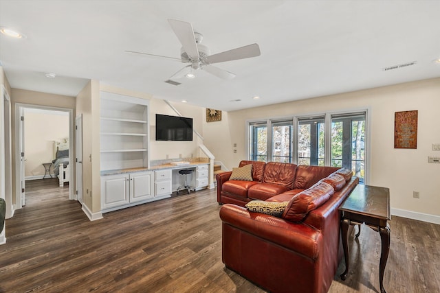 living room with dark wood-type flooring, ceiling fan, and built in shelves