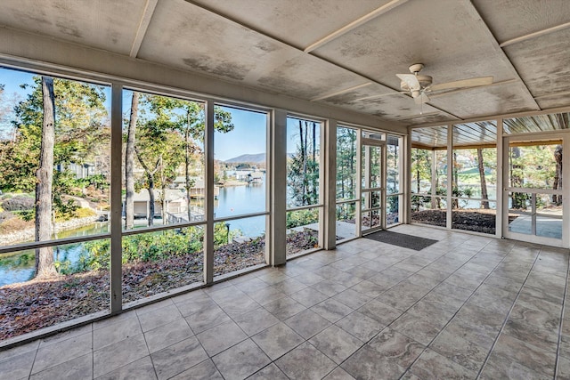 unfurnished sunroom featuring a wealth of natural light, a water and mountain view, and ceiling fan