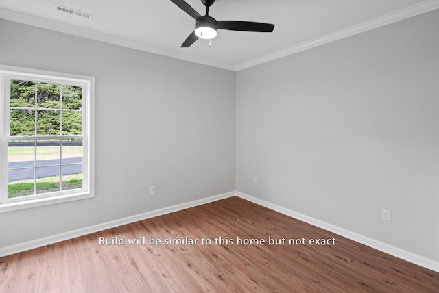 spare room with crown molding, visible vents, a ceiling fan, wood finished floors, and baseboards