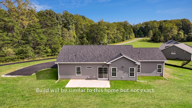 rear view of property with a patio, a lawn, a wooded view, and roof with shingles