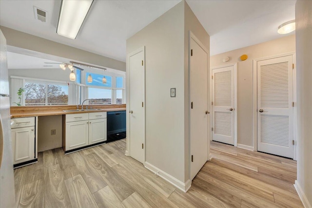 kitchen with light wood-style flooring, a sink, visible vents, baseboards, and black dishwasher