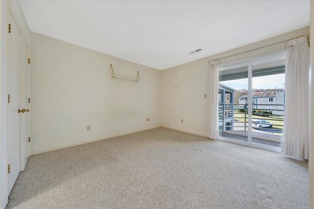 empty room featuring visible vents, light carpet, and baseboards