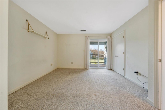 carpeted spare room featuring baseboards and visible vents