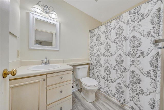 bathroom with toilet, curtained shower, wood finished floors, and vanity