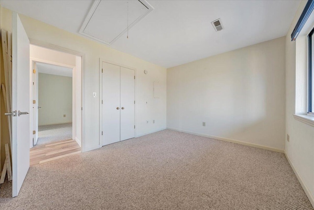 unfurnished bedroom featuring attic access, visible vents, carpet floors, and baseboards