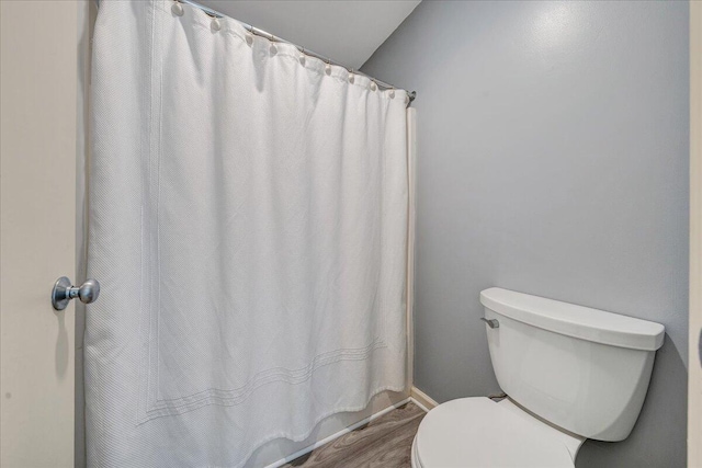 full bathroom featuring toilet, a shower with curtain, and wood finished floors