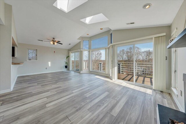 unfurnished living room featuring high vaulted ceiling, a skylight, and light hardwood / wood-style floors