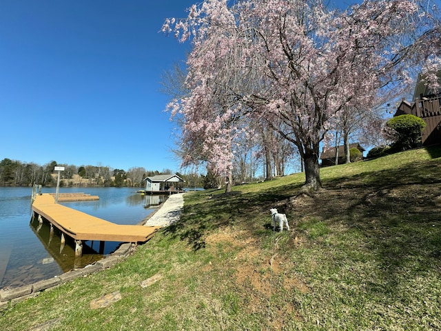 view of dock featuring a water view and a yard