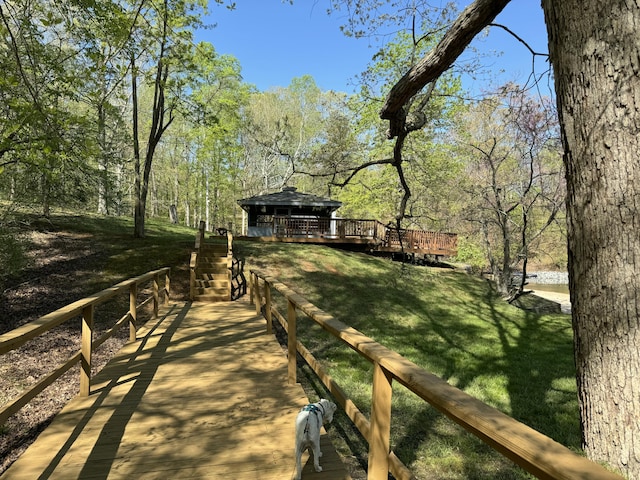 surrounding community with a deck, a yard, a gazebo, and a wooded view