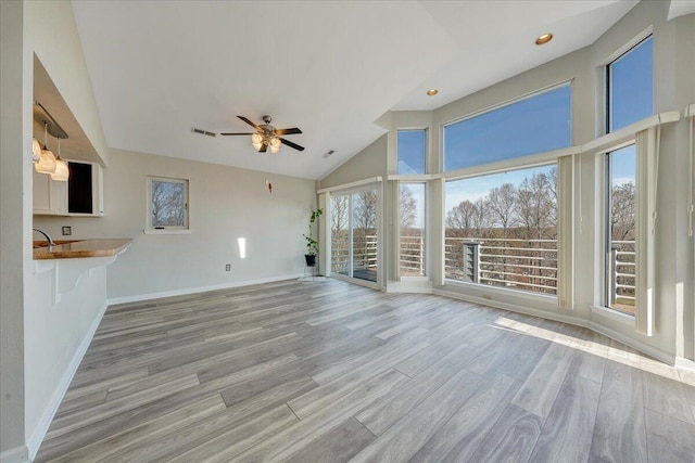 unfurnished living room with high vaulted ceiling, ceiling fan, and light wood-type flooring