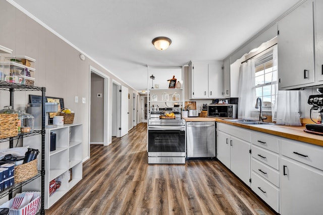 kitchen with white cabinets, crown molding, dark wood-type flooring, and appliances with stainless steel finishes