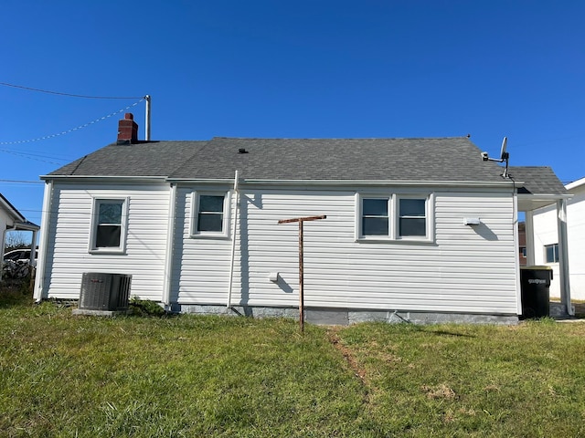 rear view of house featuring central AC unit and a yard