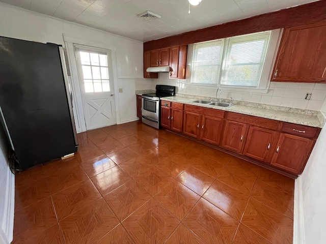 kitchen with sink, light stone counters, backsplash, fridge, and electric stove