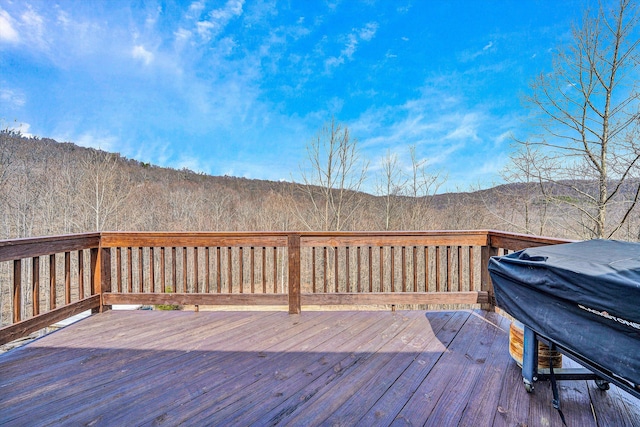 deck with a mountain view, a grill, and a wooded view