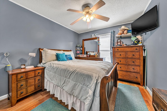 bedroom featuring light wood finished floors, a textured ceiling, crown molding, and a ceiling fan