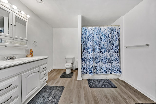 bathroom with curtained shower, toilet, vanity, and wood finished floors