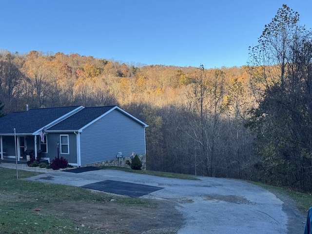 view of home's exterior with aphalt driveway and a forest view