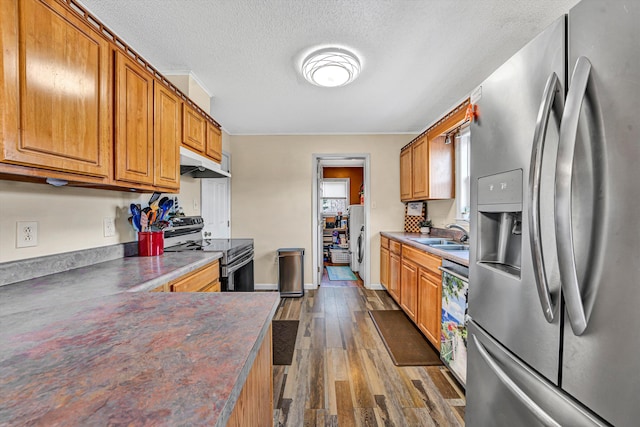 kitchen with electric range, dark wood-type flooring, under cabinet range hood, dark countertops, and stainless steel fridge