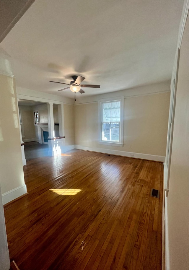 unfurnished living room with hardwood / wood-style floors, ceiling fan, crown molding, and a fireplace