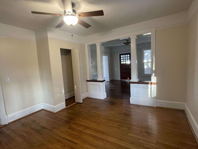 unfurnished room with dark hardwood / wood-style floors, ornate columns, and ceiling fan