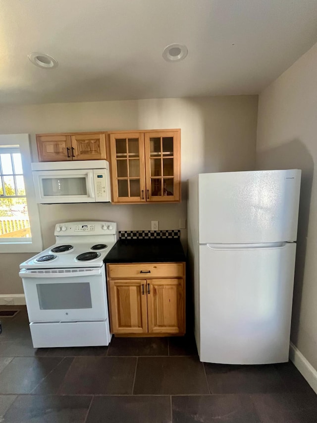 kitchen featuring white appliances and dark tile patterned floors