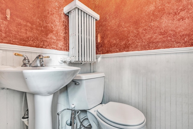 bathroom featuring wood walls and toilet