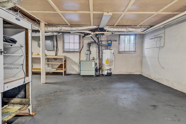 basement featuring electric panel, plenty of natural light, and water heater