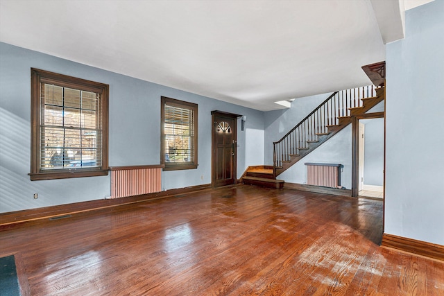 entryway with hardwood / wood-style floors, a healthy amount of sunlight, and radiator heating unit