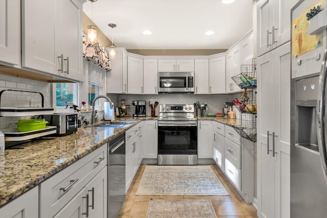 kitchen with decorative backsplash, stainless steel appliances, sink, pendant lighting, and white cabinetry