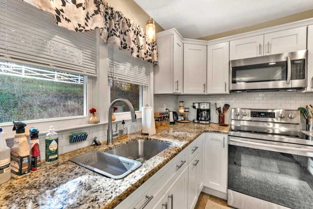 kitchen with white cabinets, hanging light fixtures, sink, appliances with stainless steel finishes, and tasteful backsplash