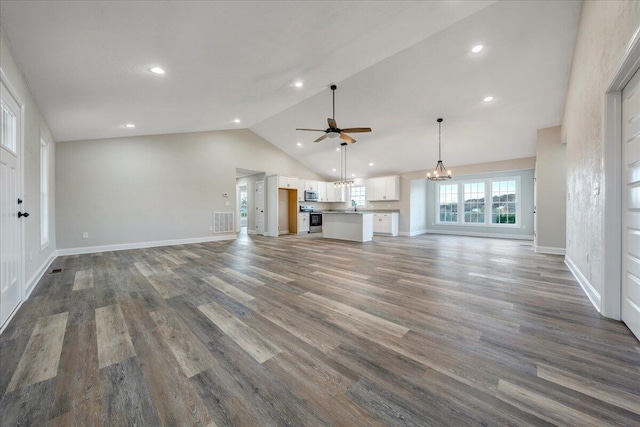 unfurnished living room with ceiling fan with notable chandelier, dark hardwood / wood-style floors, and high vaulted ceiling