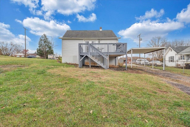 rear view of house with a carport, a lawn, and a wooden deck