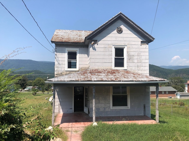 bungalow-style home with a mountain view, a front lawn, and a patio