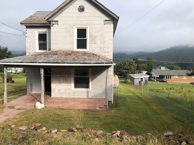 back of property with a mountain view, a yard, and a patio