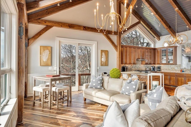 living room featuring a notable chandelier, a healthy amount of sunlight, and high vaulted ceiling