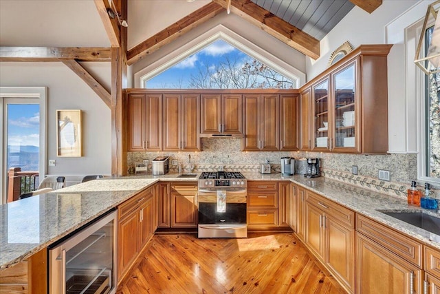 kitchen with tasteful backsplash, light stone countertops, wine cooler, and stainless steel gas range