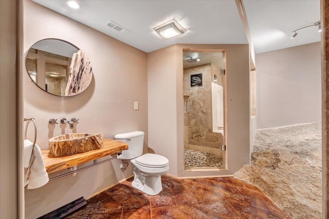 bathroom featuring toilet, an enclosed shower, and sink