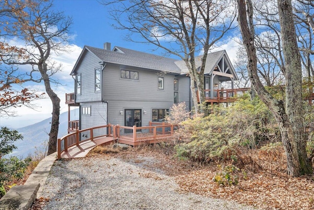 back of property with a deck with mountain view and french doors