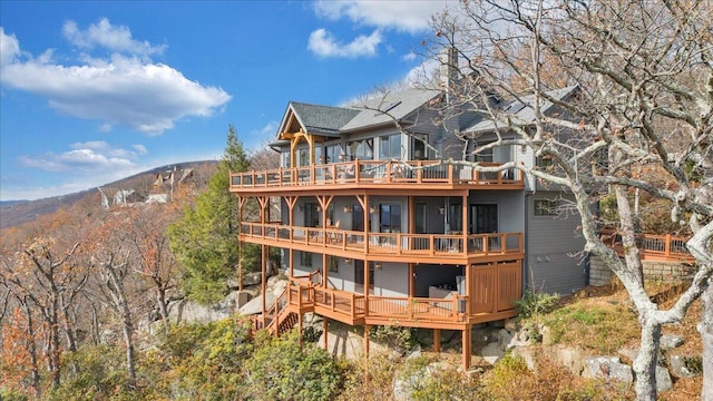 rear view of property featuring a sunroom and a deck with mountain view