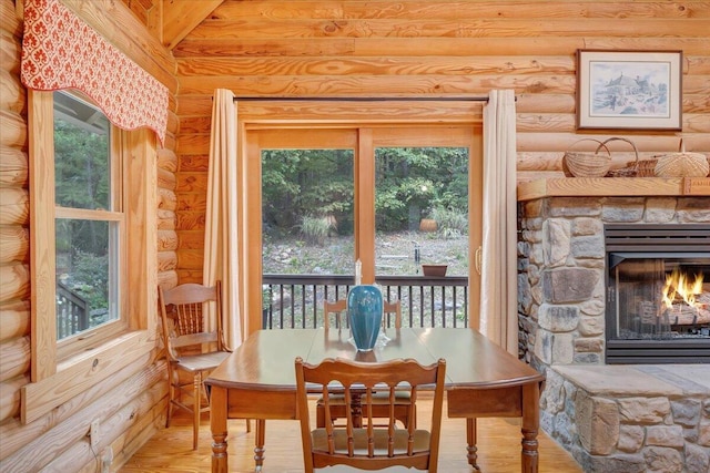 dining space with a fireplace, rustic walls, and light wood-type flooring