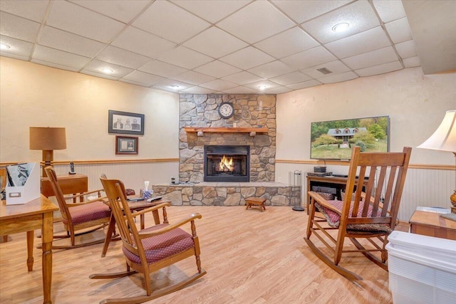 sitting room with a drop ceiling, a fireplace, and light hardwood / wood-style floors