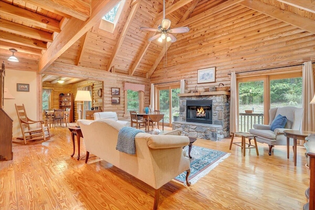 living room featuring beam ceiling, wood ceiling, light hardwood / wood-style flooring, ceiling fan, and a fireplace