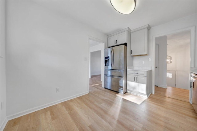 kitchen featuring stainless steel fridge, white cabinets, and light wood-type flooring