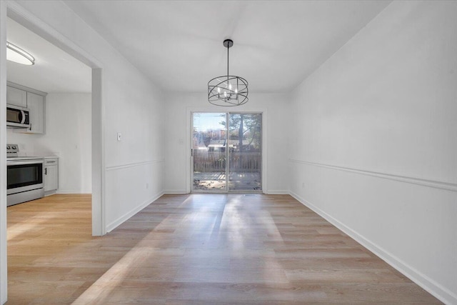 unfurnished dining area with light wood-type flooring and a notable chandelier