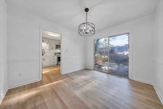 unfurnished dining area featuring light hardwood / wood-style flooring, a notable chandelier, and sink