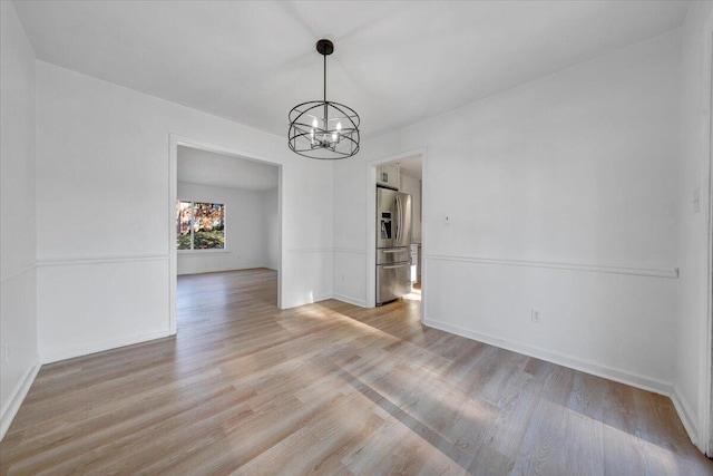 unfurnished dining area featuring a chandelier and light wood-type flooring