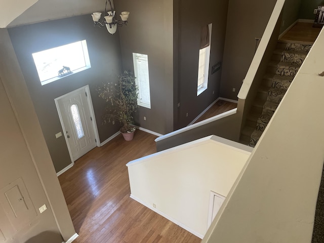 entrance foyer with a notable chandelier, stairway, baseboards, and wood finished floors