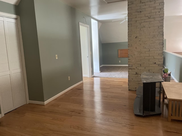 interior space featuring lofted ceiling, baseboards, and light wood finished floors